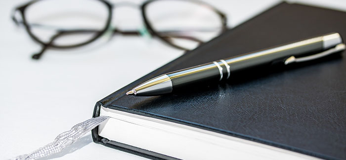 Stock photo of a notepad and reading glasses.